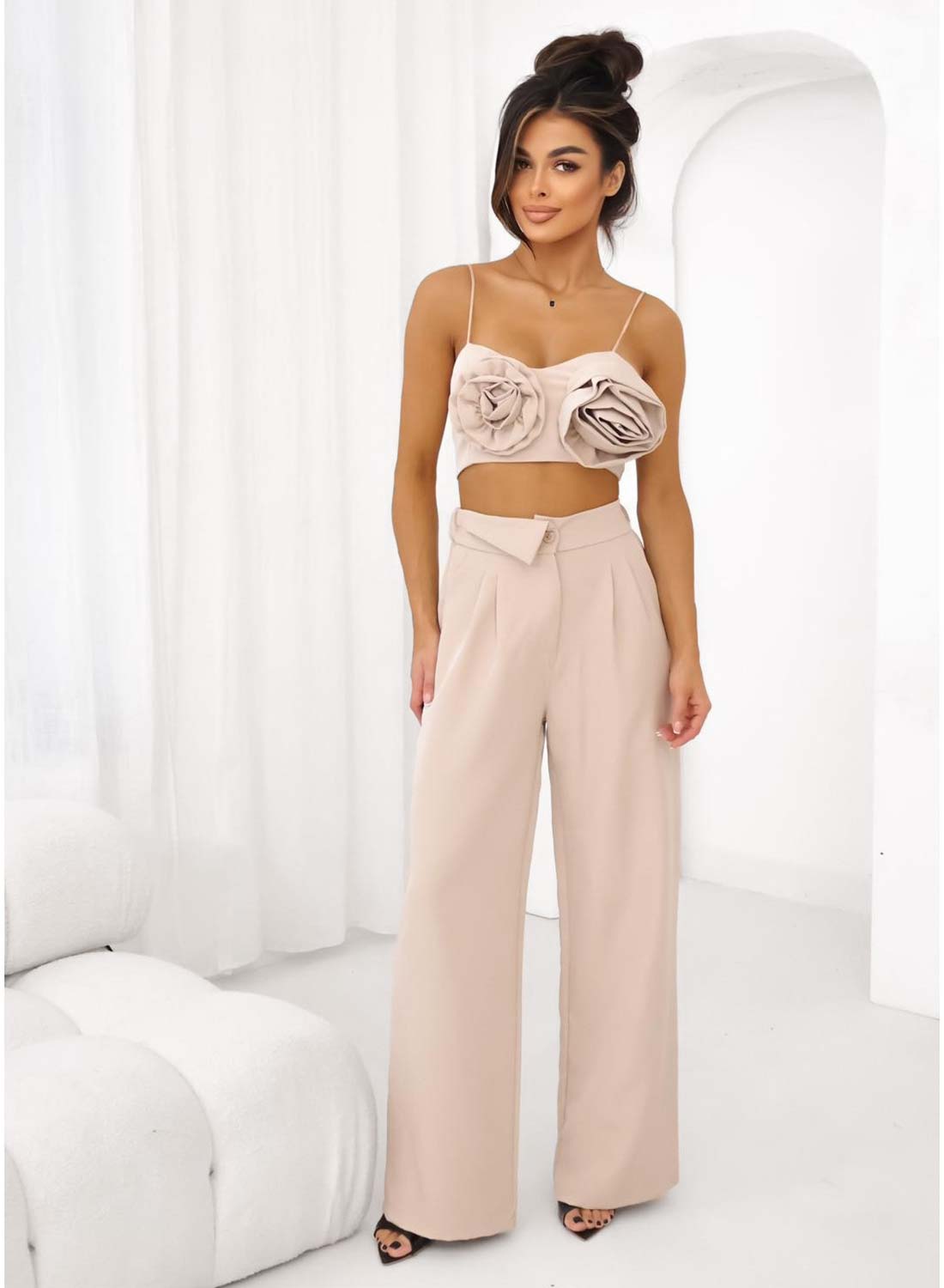 Woman wearing a beige crop top with large 3D floral appliqués and spaghetti straps