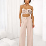 Woman wearing a beige crop top with large 3D floral appliqués and spaghetti straps