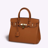 Tan structured tote bag with gold lock detail and top handles on a plain background