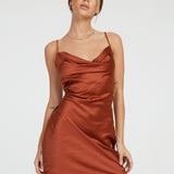 Woman wearing dark rust satin mini slip dress with cowl neckline and spaghetti straps