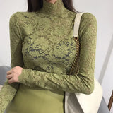 Woman wearing a green lace turtleneck top with long sleeves and floral mesh detailing