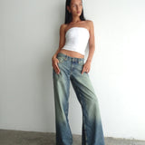 Woman wearing oversized low-rise wide leg jeans in extreme blue green with a white tube top