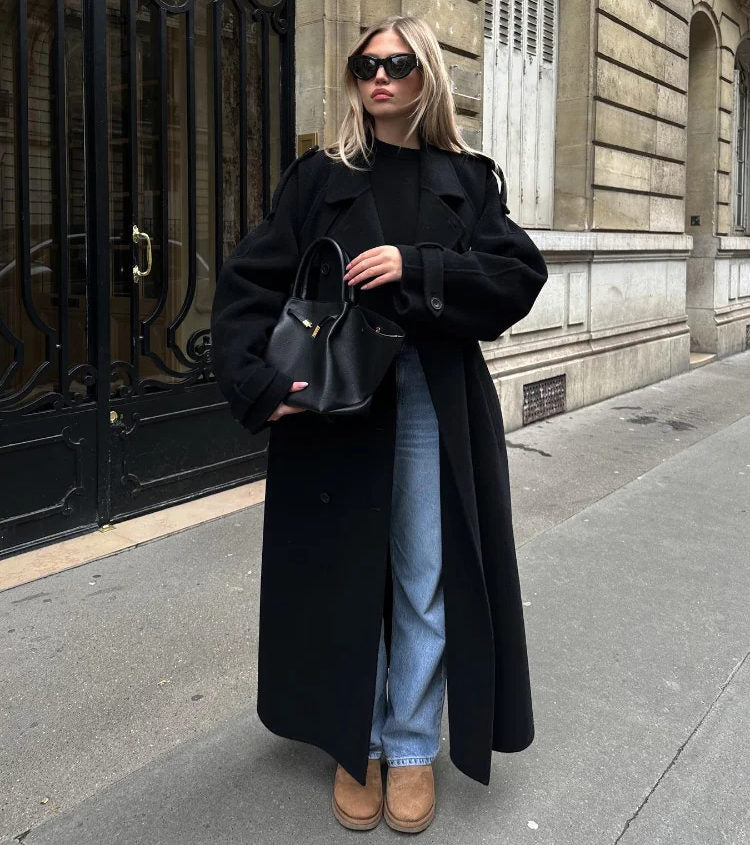 Woman wearing oversized black wool longline coat with jeans and boots, styled for chic winter street fashion